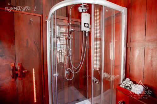 La salle de bains est pourvue d'une douche avec une porte en verre. dans l'établissement Baan Lhang Wangh บ้านหลังวัง, à Phitsanulok