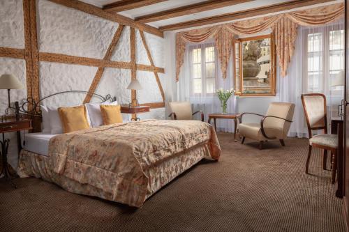 una camera con letto, sedie e finestre di Promenáda Romantic Hotel a Karlovy Vary