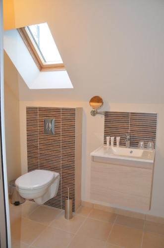 La salle de bains est pourvue de toilettes, d'un lavabo et d'une lucarne. dans l'établissement Auberge du Moulin à Vent, The Originals Relais, à Manou