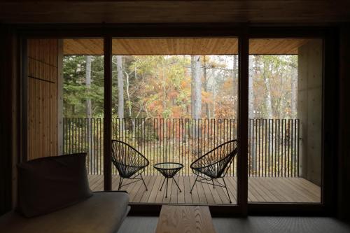 a screened in porch with two chairs and a table at Regina Resort Kyukaruizawa in Karuizawa