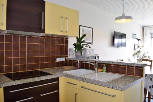 - une cuisine avec des placards jaunes et un évier dans l'établissement Appartement 2-4 pers VUE MER EXCEPTIONNELLE avec terrasse à PERROS-GUIREC - Ref 908, à Perros-Guirec