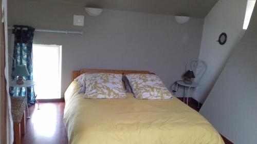 a bedroom with a bed with yellow sheets and a window at LA LAMBERTERIE : LA BOULANGERIE in Yvetot Bocage