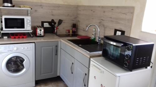 a kitchen with a microwave and a sink and a washing machine at LA LAMBERTERIE : LA BOULANGERIE in Yvetot Bocage