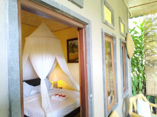 a bedroom with a bed with curtains and a window at Kanda Homestay in Sidemen