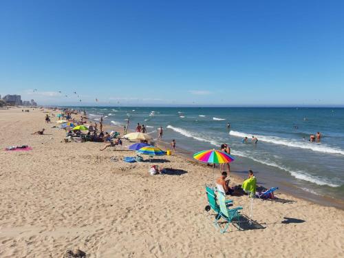 a group of people on a beach with umbrellas at Hostal El Perelló, Valencia in El Perelló
