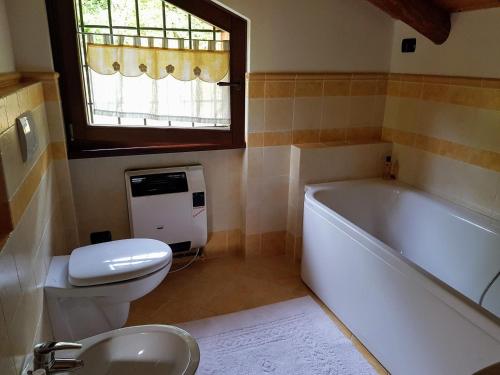 a bathroom with a tub and a toilet and a sink at Baita Eleonora in Argegno