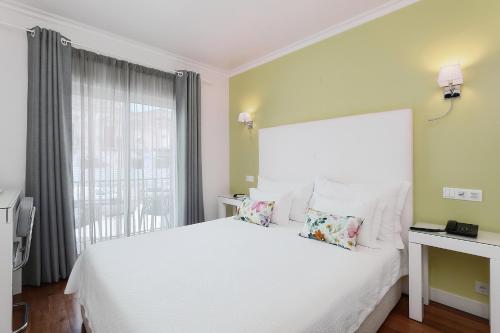 a bedroom with a white bed and a window at Vila Sao Vicente Boutique (Adults Only) in Albufeira