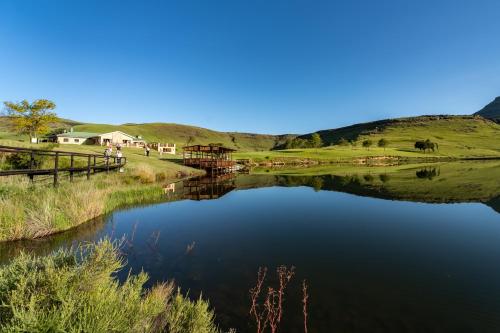 a view of a lake with a fence and houses at Gooderson Drakensberg Gardens Golf & Spa Resort in Drakensberg Garden