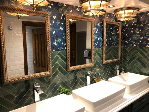a bathroom with three sinks and mirrors on the wall at The Greyhound Inn in Gerrards Cross