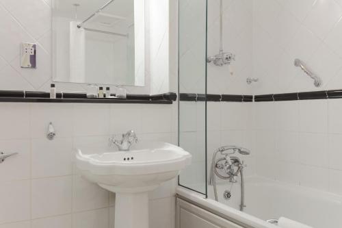 a white bathroom with a sink and a shower at The Worcester Whitehouse Hotel in Worcester