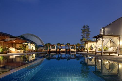 a swimming pool with chairs and a building at Aryaduta Bandung in Bandung