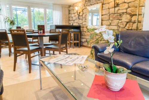a living room with a glass table with a vase with flowers at Hotel Bürger in Siegen