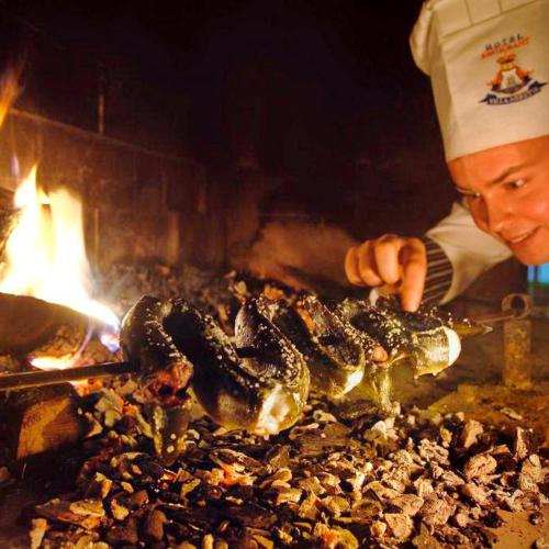 a chef cooking food on top of a grill at Hotel Villa Neretva - Metković in Metković