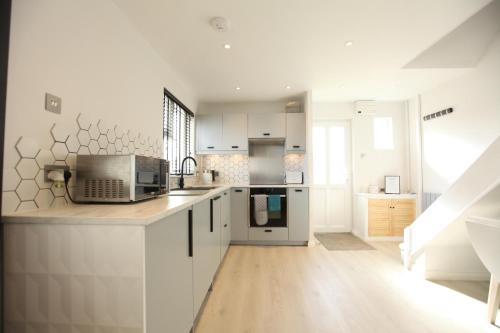 a kitchen with white cabinets and a microwave at Stylish Cambridge Pad in Bar Hill
