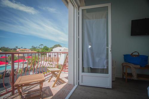 a room with a balcony with a sliding glass door at Hôtel Le Vert Bois in Dolus d'Oléron