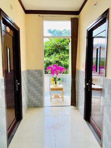 a hallway with a door and a vase of flowers on a table at Mekong Rose Hotel in Can Tho
