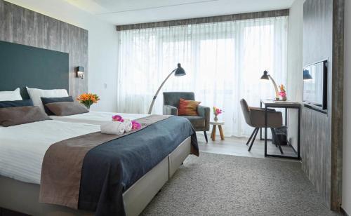 a hotel room with a large bed and a desk at Hotel Restaurant Eeserhof in Ees