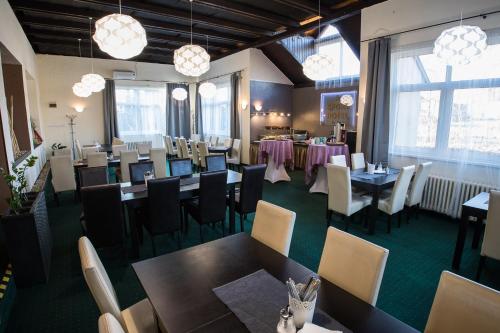 un comedor con mesas, sillas y ventanas en A-Sport Hotel, en Brno