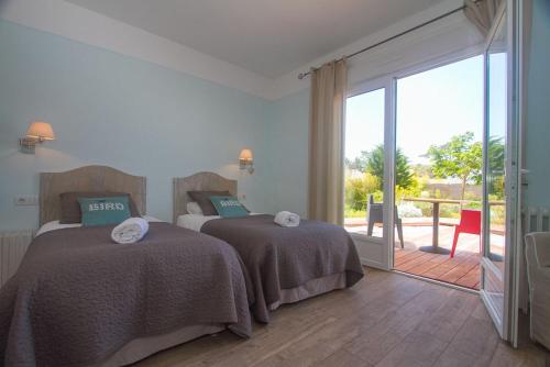a bedroom with two beds and a sliding glass door at Hôtel Le Vert Bois in Dolus d'Oléron