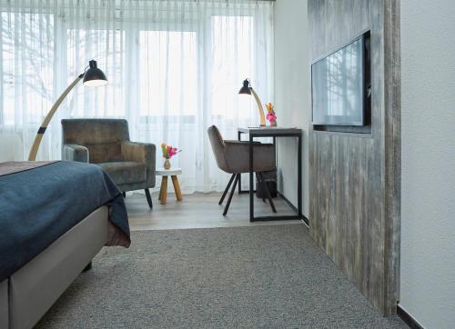 a bedroom with a bed and a desk and a chair at Hotel Restaurant Eeserhof in Ees