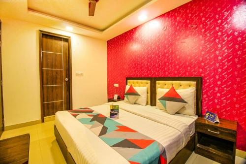 Un dormitorio con una cama y una pared roja. en FabHotel TP Suites, en Nueva Delhi