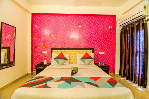 um quarto com uma cama grande e uma parede rosa em FabExpress T P Suite em Nova Deli