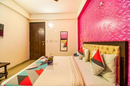 um quarto com uma cama grande e uma parede rosa em FabExpress T P Suite em Nova Deli