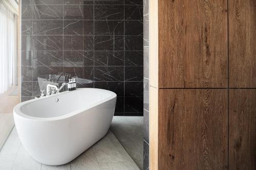 a white bath tub in a bathroom with black tiles at UMITO Okinawa Onnason in Onna