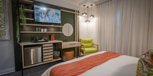 a bedroom with a bed and a tv and a chair at Villa Bali Luxury Guesthouse in Bloemfontein