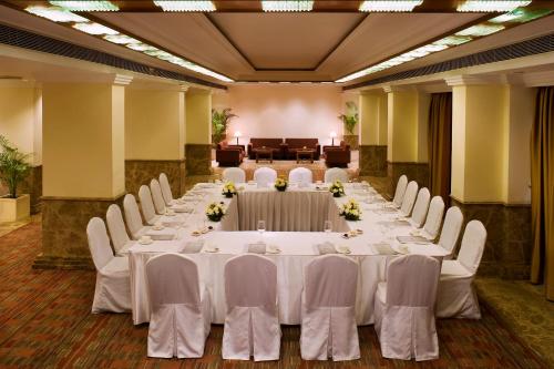 a large banquet hall with white tables and chairs at The Suryaa New Delhi in New Delhi