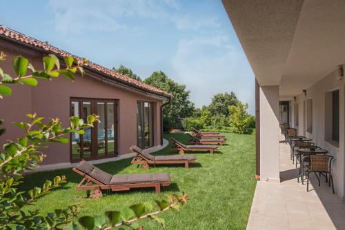 a row of benches on a lawn next to a building at Zaara Estate Winery Hotel & SPA in Glavan