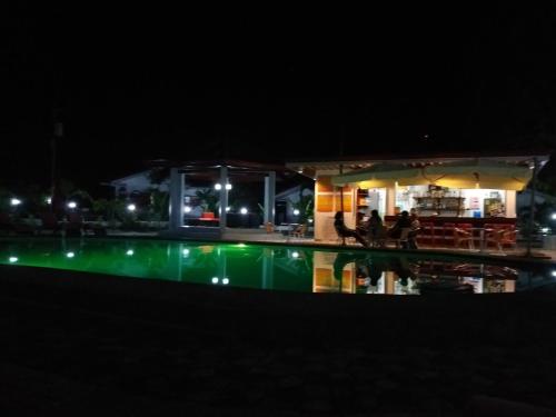 a swimming pool at night with a restaurant in the background at Garden Village Resort in Moalboal