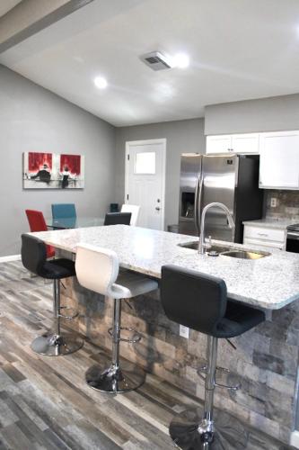 a kitchen with a counter with chairs and a sink at CYC Eclectic Escape in San Antonio