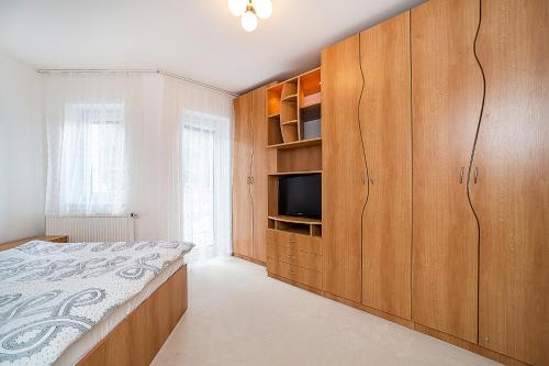 a bedroom with a bed and a tv and wooden cabinets at Apartmán V Srdci Pece in Pec pod Sněžkou