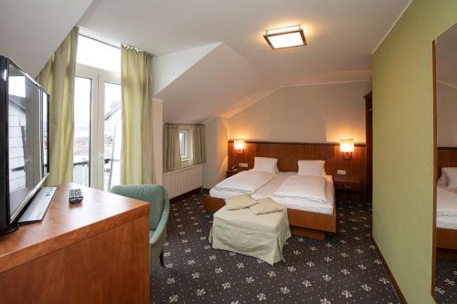 a hotel room with two beds and a television at Keramikhotel Goldener Brunnen in Gmunden