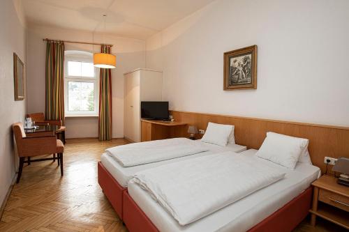 a bedroom with a bed and a desk and a television at Keramikhotel Goldener Brunnen in Gmunden