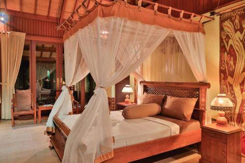 a bedroom with a canopy bed with white curtains at Villa Bulan Madu Gili Air in Senaru