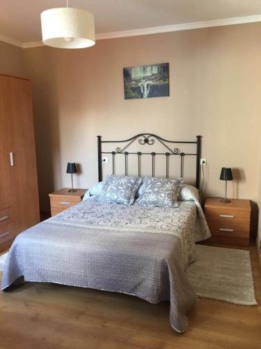 1 dormitorio con 1 cama grande y 2 mesitas de noche en Pisos Turísticos Muxía -Teresa Barros, en Muxía