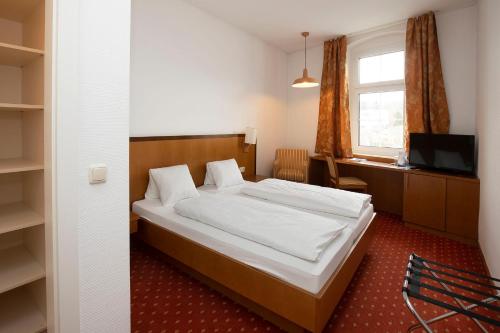a bedroom with a bed and a desk and a television at Keramikhotel Goldener Brunnen in Gmunden