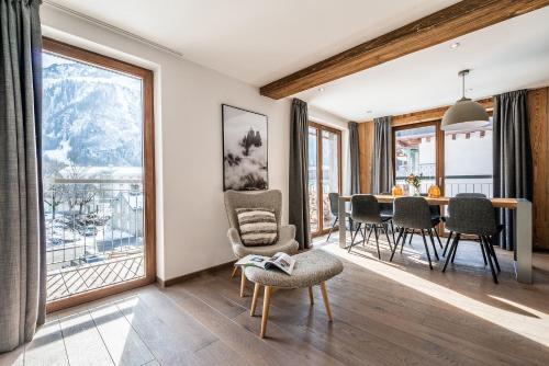 un salon avec une table, des chaises et des fenêtres dans l'établissement Le Globe Argentière Chamonix - by EMERALD STAY, à Chamonix-Mont-Blanc