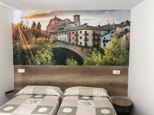 ein Schlafzimmer mit einem Wandbild einer Brücke in der Unterkunft Pensión Mavi in Los Arcos