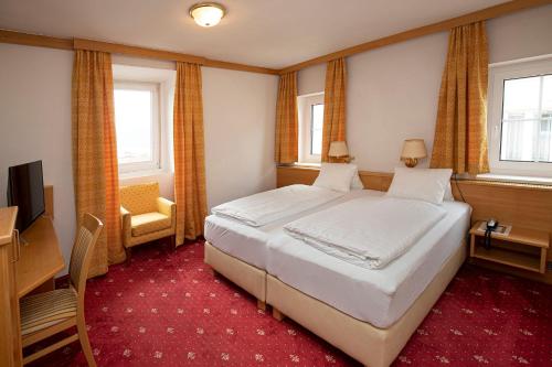 a bedroom with a bed and a desk and a television at Keramikhotel Goldener Brunnen in Gmunden