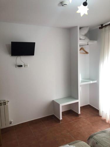 洛斯阿爾科斯的住宿－Pensión Mavi，一间客厅,在白色的墙上配有电视