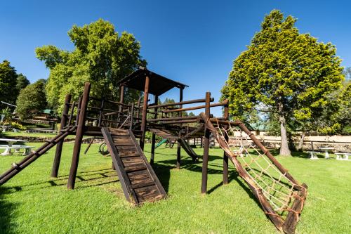 a wooden playground with a slide in a park at Gooderson Drakensberg Gardens Golf & Spa Resort in Drakensberg Garden