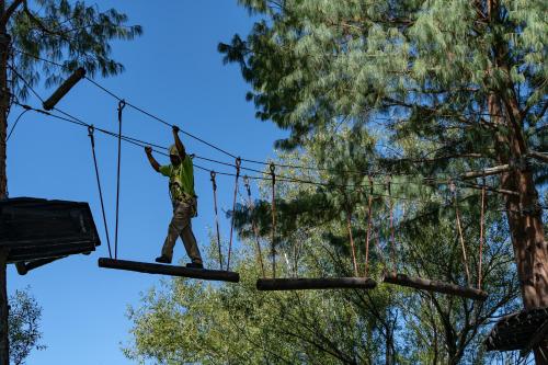a man on a zip line in front of trees at Gooderson Drakensberg Gardens Golf & Spa Resort in Drakensberg Garden