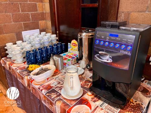 a table with cups and a coffee maker on it at Hotel Ondras z Beskyd in Ostravice