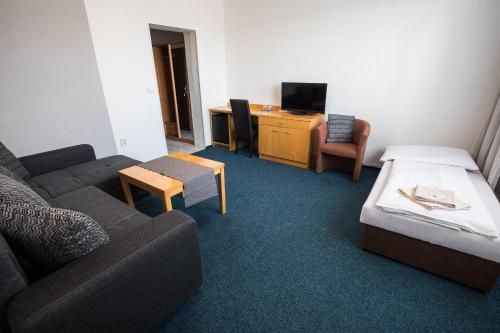 a living room with a couch and a table and a desk at A-Sport Hotel in Brno