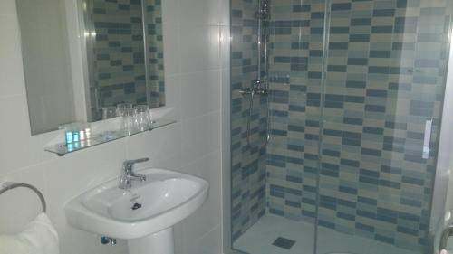 a bathroom with a sink and a glass shower at Hostal La Despensa de Extremadura in Plasencia
