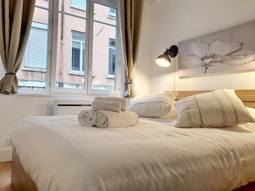 une chambre avec un grand lit blanc avec une fenêtre dans l'établissement Le Tisserand by Cocoonr, à Lyon