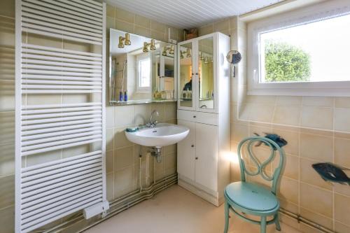 ein Badezimmer mit einem Waschbecken, einem Stuhl und einem Fenster in der Unterkunft CABESTAN - Maison de famille au coeur du bourg - Vue Mer in Carantec